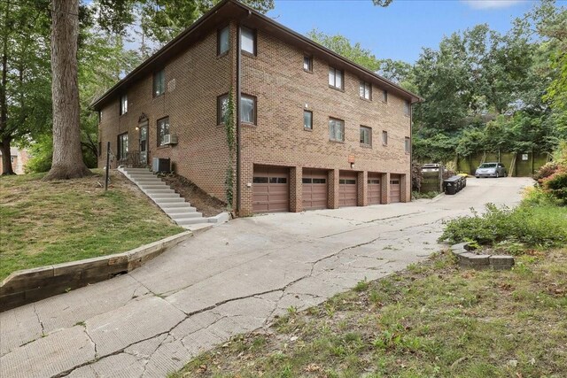 view of side of home with cooling unit, a garage, and central air condition unit