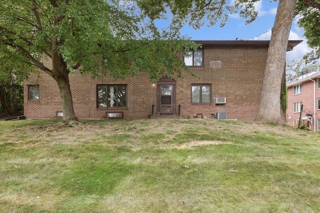 back of property featuring a yard, brick siding, and central AC