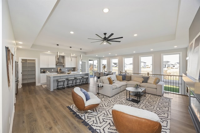 living room with a tray ceiling, ceiling fan, and dark hardwood / wood-style flooring