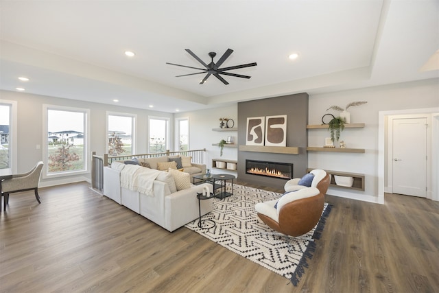 living room featuring hardwood / wood-style floors, ceiling fan, and a raised ceiling