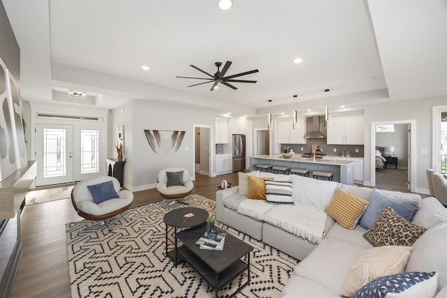 living room with a tray ceiling, ceiling fan, french doors, and hardwood / wood-style flooring