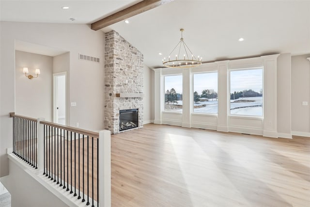 unfurnished living room with a fireplace, lofted ceiling with beams, light wood-type flooring, and a notable chandelier