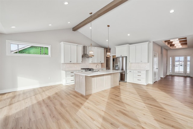 kitchen with decorative backsplash, stainless steel fridge, a kitchen island with sink, and pendant lighting