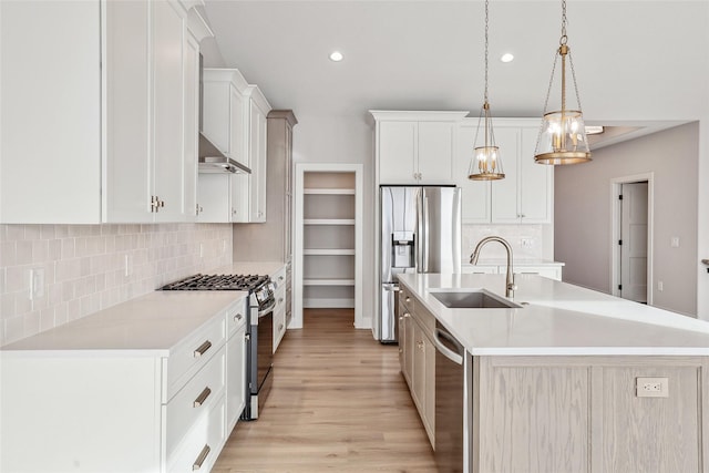 kitchen featuring pendant lighting, a center island with sink, white cabinets, sink, and stainless steel appliances