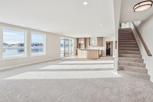 unfurnished living room with light carpet and a water view