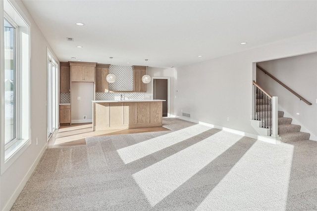 kitchen with light carpet, pendant lighting, a center island, and tasteful backsplash