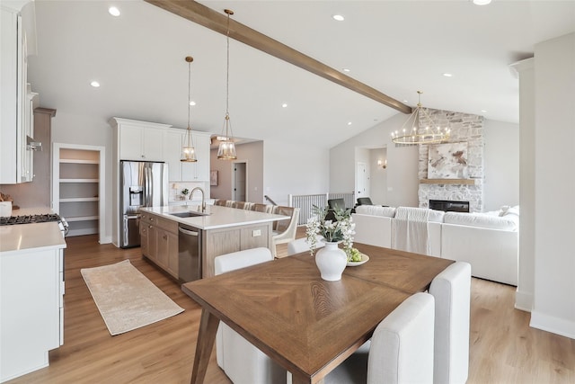 dining space with a fireplace, light wood finished floors, recessed lighting, high vaulted ceiling, and beamed ceiling