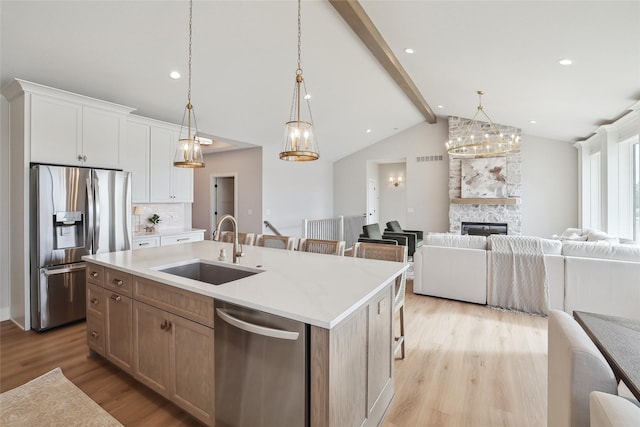 kitchen featuring a center island with sink, appliances with stainless steel finishes, open floor plan, and a sink