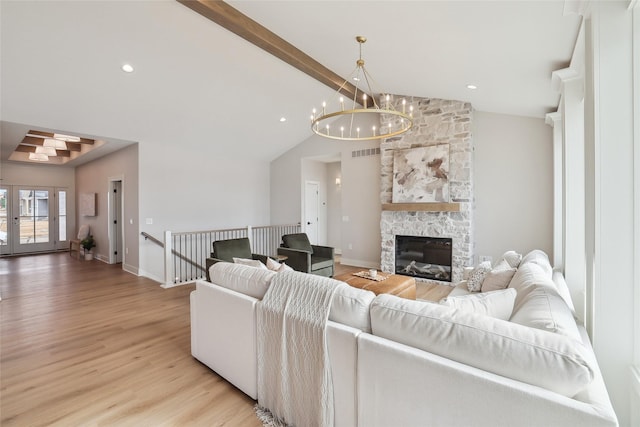 living area featuring light wood-style flooring, a fireplace, visible vents, baseboards, and beam ceiling