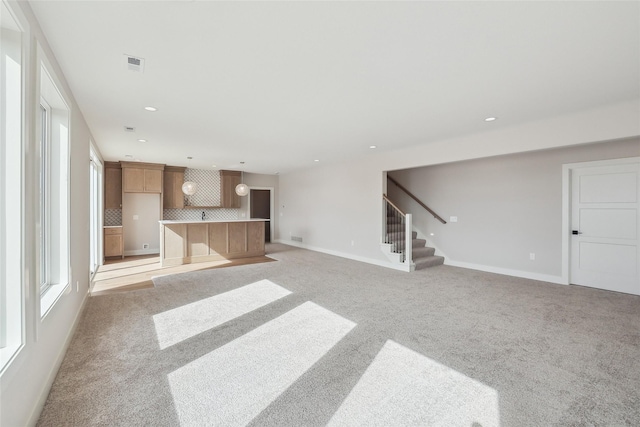 living area with baseboards, visible vents, stairway, and light colored carpet