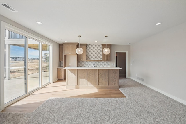 kitchen featuring visible vents, decorative backsplash, a center island, hanging light fixtures, and light countertops