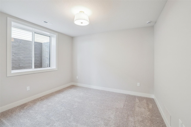 empty room featuring carpet, visible vents, and baseboards