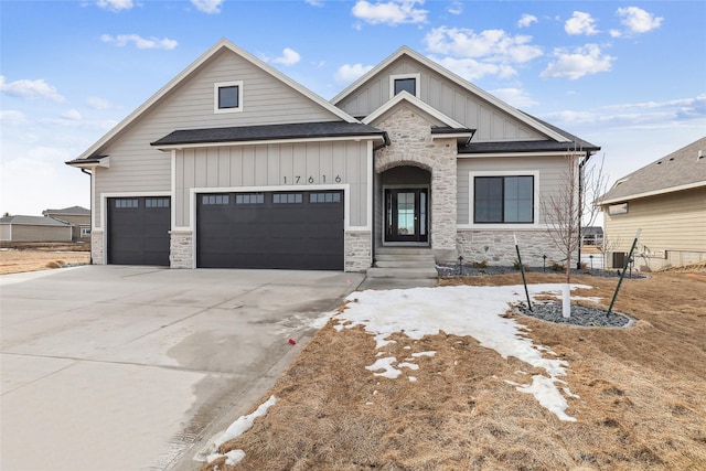 view of front of property featuring a garage, a shingled roof, driveway, stone siding, and board and batten siding