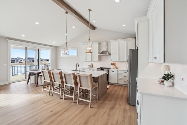 kitchen with wall chimney exhaust hood, appliances with stainless steel finishes, light countertops, and white cabinetry