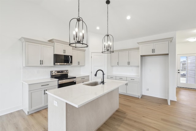 kitchen featuring stainless steel appliances, light hardwood / wood-style flooring, a center island with sink, and sink