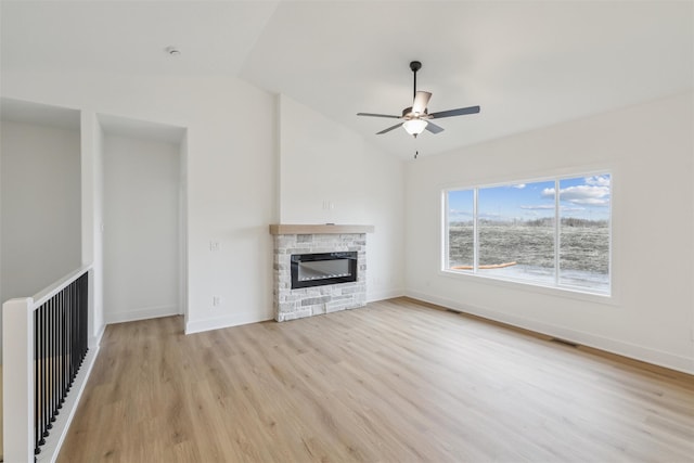 unfurnished living room with a stone fireplace, ceiling fan, light hardwood / wood-style floors, and vaulted ceiling