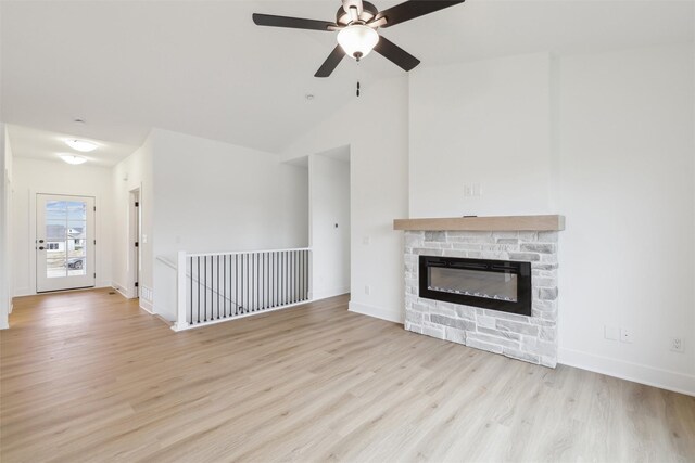 unfurnished living room featuring ceiling fan, light wood-type flooring, a fireplace, and vaulted ceiling