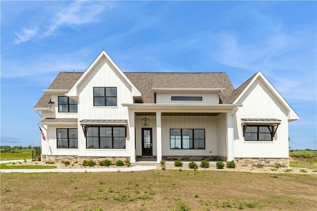 modern inspired farmhouse featuring a shingled roof, a front lawn, and board and batten siding