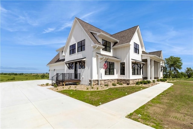 view of side of home featuring driveway, a lawn, board and batten siding, and roof with shingles