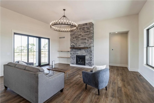 living room featuring a notable chandelier, a healthy amount of sunlight, a fireplace, and dark hardwood / wood-style flooring