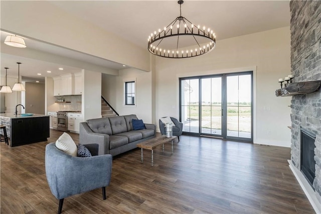 living area with dark wood-style flooring, a fireplace, stairway, and baseboards