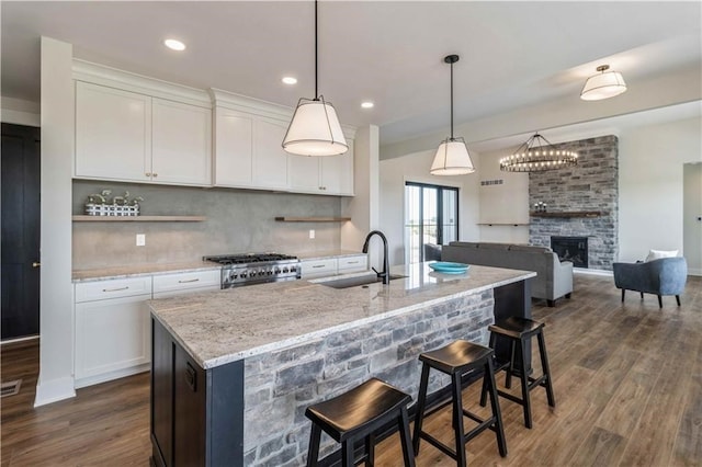 kitchen with sink, a fireplace, dark wood-type flooring, and pendant lighting