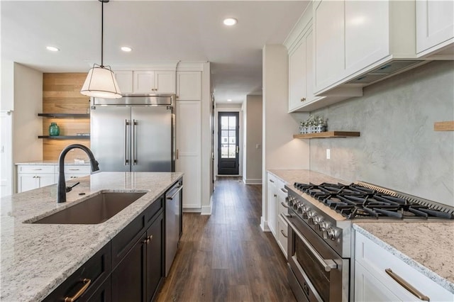 kitchen with high end appliances, sink, white cabinets, and light stone counters