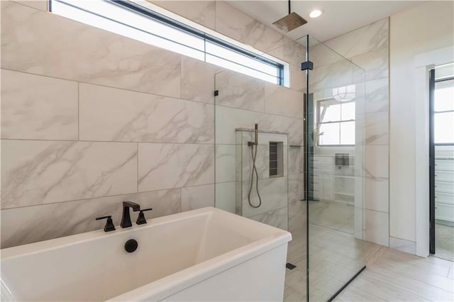 bathroom featuring a soaking tub, a sink, tile walls, and walk in shower