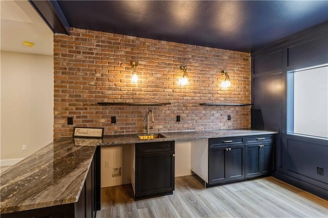 bar with beam ceiling, sink, light hardwood / wood-style floors, and dark stone counters