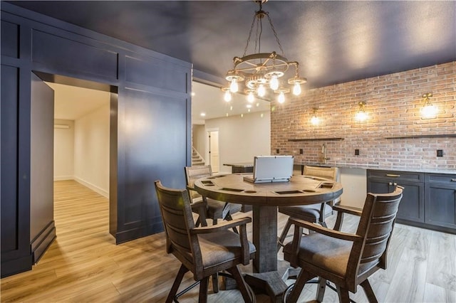 dining room featuring baseboard heating, brick wall, and light wood-type flooring