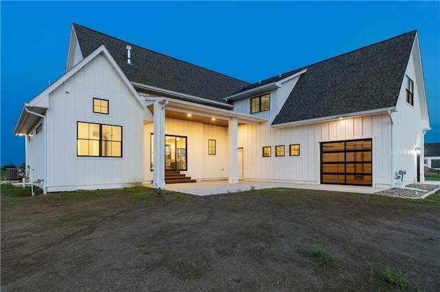 rear view of house with driveway, a shingled roof, an attached garage, cooling unit, and board and batten siding