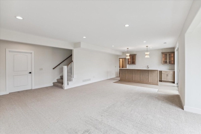 unfurnished living room with recessed lighting, light carpet, visible vents, baseboards, and stairway