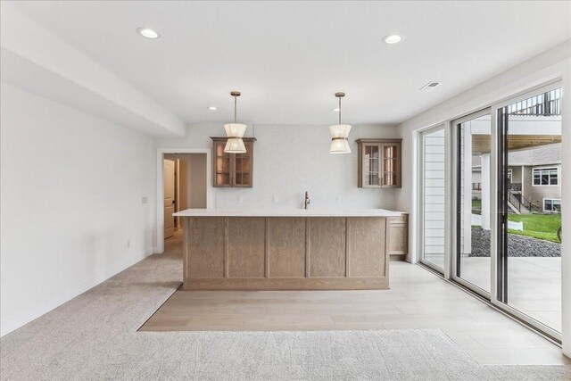 kitchen featuring recessed lighting, baseboards, a center island, glass insert cabinets, and pendant lighting