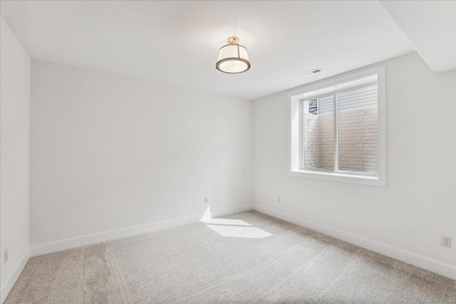 spare room featuring light carpet and baseboards