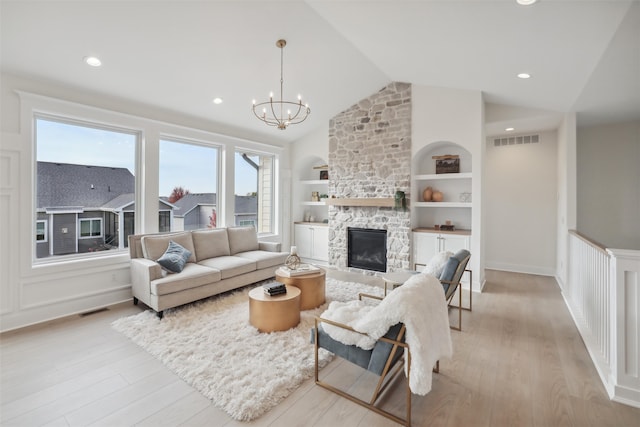 living room featuring built in features, vaulted ceiling, visible vents, and a fireplace