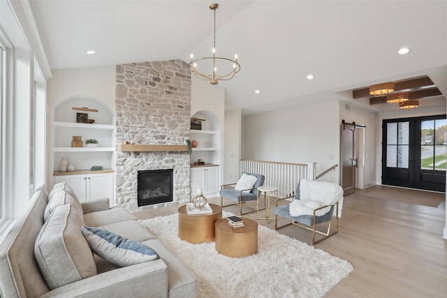 living area with built in features, lofted ceiling, a chandelier, and light wood-style floors