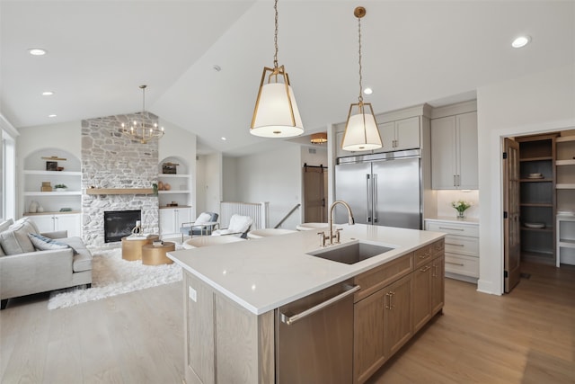 kitchen with appliances with stainless steel finishes, lofted ceiling, a sink, and light wood finished floors