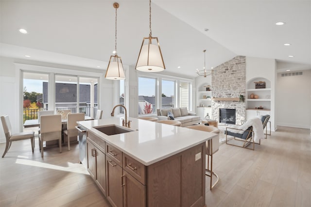 kitchen with lofted ceiling, light wood-style floors, visible vents, and built in features