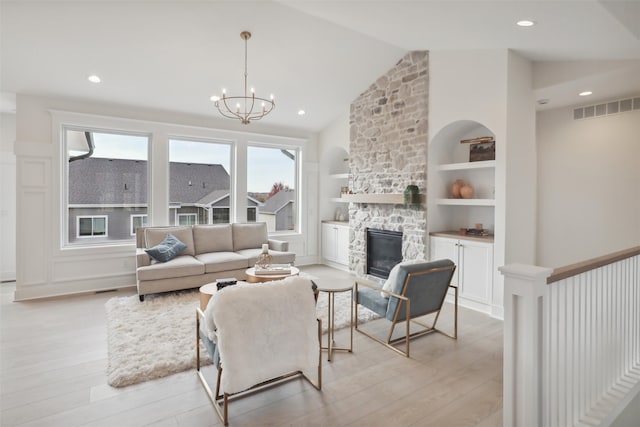 living area with built in shelves, visible vents, light wood-style floors, and a fireplace