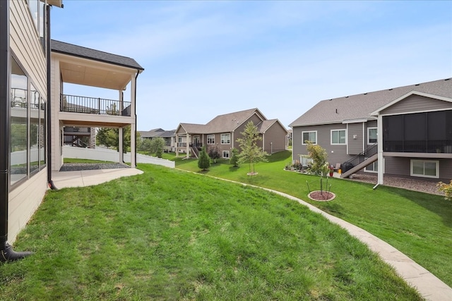 view of yard featuring a balcony, a sunroom, and a residential view