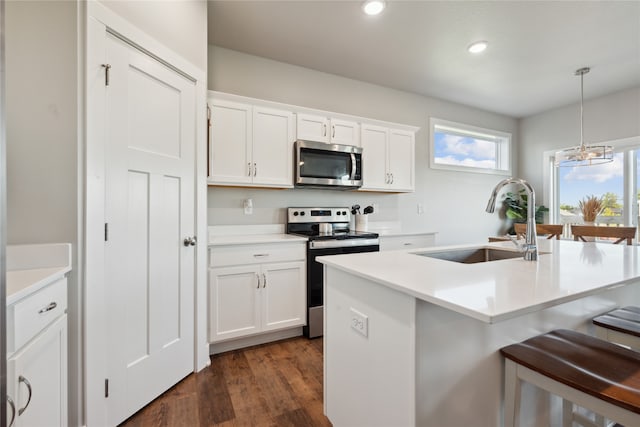 kitchen featuring stainless steel appliances, sink, decorative light fixtures, white cabinets, and a chandelier