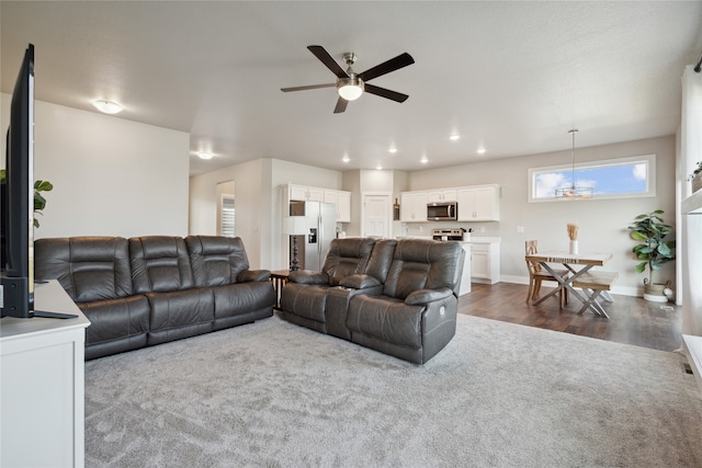 living room featuring ceiling fan with notable chandelier and dark hardwood / wood-style flooring