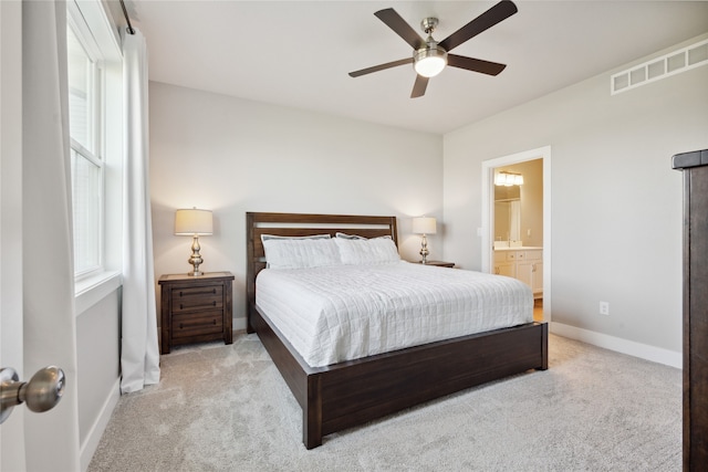 carpeted bedroom with ensuite bath and ceiling fan