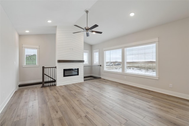 unfurnished living room featuring ceiling fan, a fireplace, lofted ceiling, and light wood-type flooring