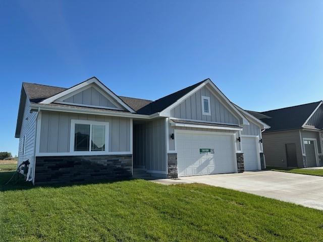 view of front facade featuring an attached garage, board and batten siding, driveway, and a front yard