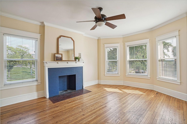 unfurnished living room with light wood-type flooring, a brick fireplace, ceiling fan, and crown molding