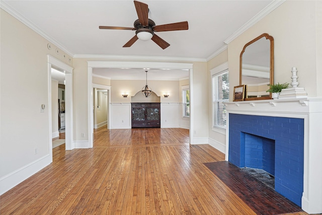 unfurnished living room featuring ceiling fan, a fireplace, wood-type flooring, and ornamental molding