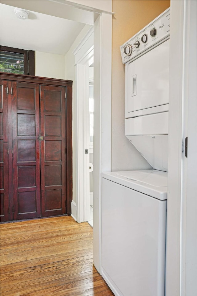 washroom with light hardwood / wood-style floors and stacked washer and clothes dryer