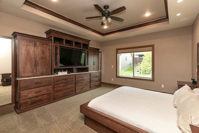 carpeted bedroom with a tray ceiling and ceiling fan