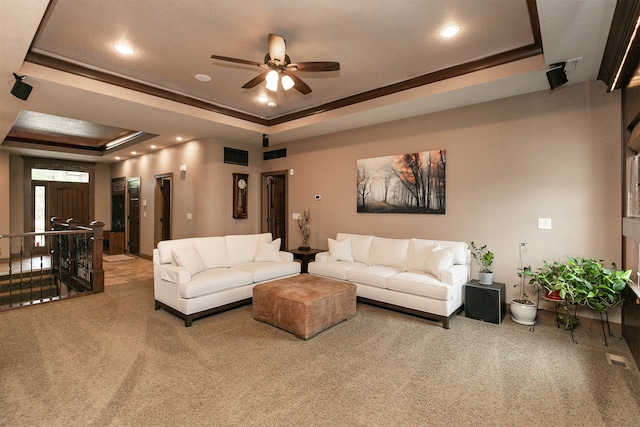 carpeted living room with ceiling fan, ornamental molding, and a tray ceiling